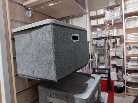 Grey herringbone pattern storage box with a metal handle sits on a retail s.. Stock Photos