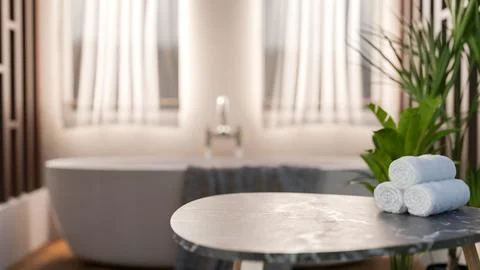 A grey marble tabletop with towels with blurry background of bathtub beside.. Stock Illustration