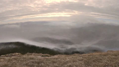 Grey misty clouds moving over grassy mountains nature at windy sunrise Stock Footage 144552164