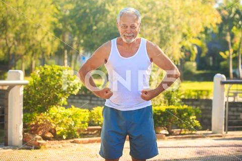 Grey Old Man in Vest Strains Arms Musculars Smiles in Park Stock Photos