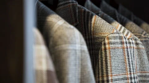 Grey patterned tweed jackets hanging in wooden wardrobe, close up. Stock Footage 205451014