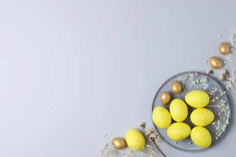 Grey plate with easter yellow eggs and flowers on grey background. Flat lay,  Foto stock