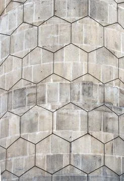 Grey polygon hexagonal pattern on an old curved concrete block exterior wall Stock Photos