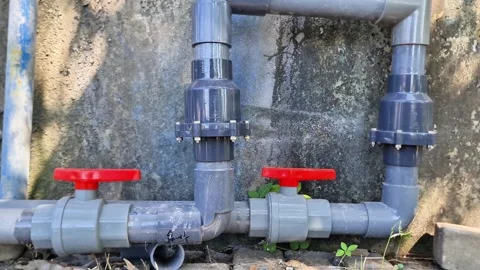 Grey PVC plumbing system featuring red handle ball valves 動画素材 339391486