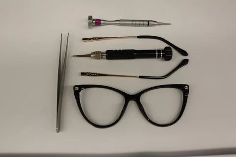 Grey rectangle glasses on table with tweezers and screwdriver Stock Photos