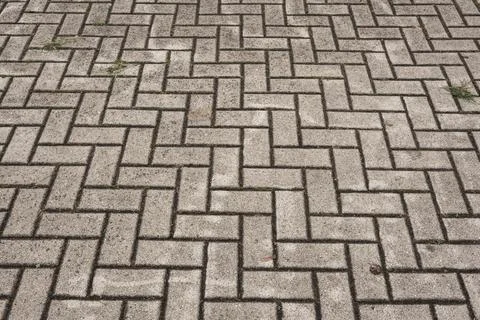 Grey rectangular brick pavers creating herringbone pattern on a paved ground Stock Photos