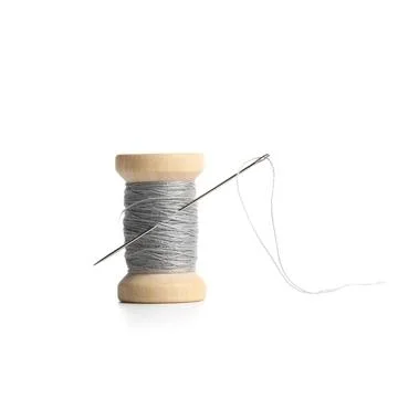 Grey sewing thread spool with needle isolated on white background, closeup Stock Photos
