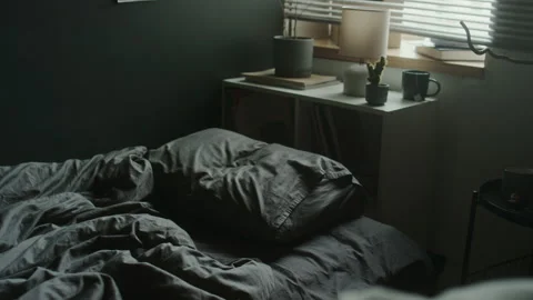 Grey Sheets of Messy Bed and White Cabinet with Shelves near Dark Wall Stock Footage 284241892