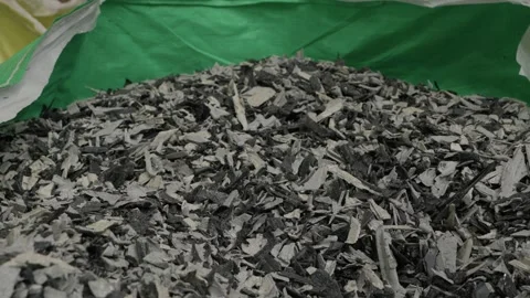 Grey shredded plastic regrind inside open bulk bag at recycling plant Stock Footage 345288002