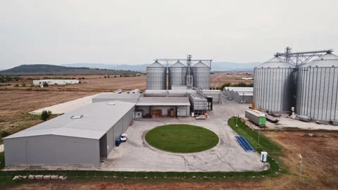 Grey Silos Wheat Bread Production Plant Fly Through Small Gap Rural Village in Stock Footage 237356667