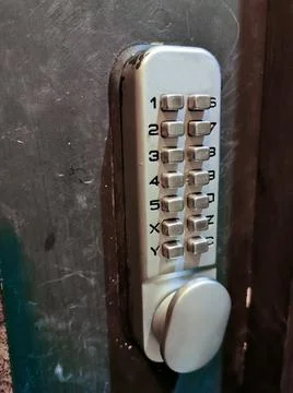 Grey silver number keypads security door locker on black door Stock Photos