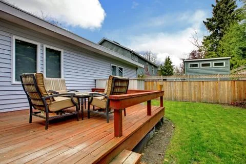 Grey small house with simple deck and outdoor chairs. Stock Photos