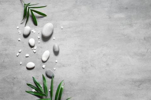 Grey spa background, spa concept, palm leaves and grey stones, top view. Stock Photos