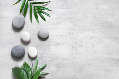 Grey spa background, spa concept, palm leaves and grey stones. Stock Photos