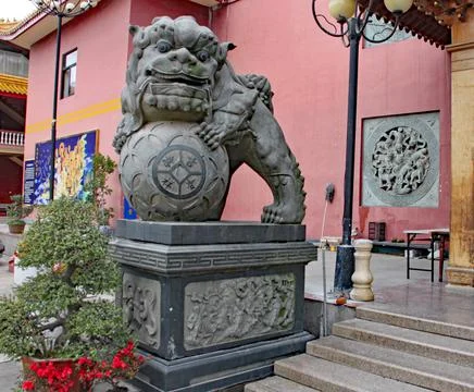 A grey statue of a lion guards the steps into the temple in Xiamen in China 스톡 사진