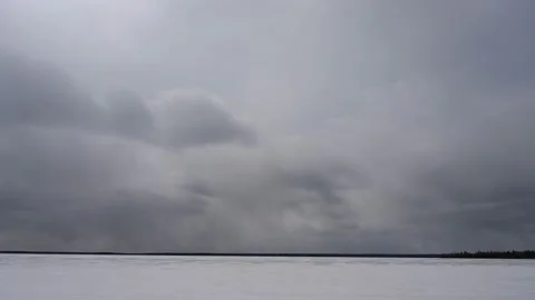 Grey storm clouds move above a frozen lake that is covered by snow. Stock Footage 152744392