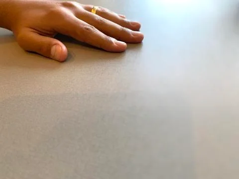 A grey table, a man's hand, and a gold ring shining Foto stock
