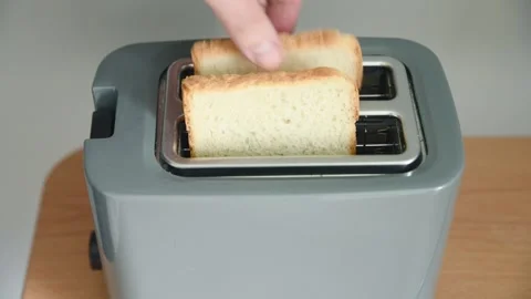 Grey toaster with glowing heating elements toasting bread slices on wooden .. Stock Footage 334570299