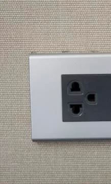 Grey universal electricity sockets plug on a yellow wall. Stock Photos