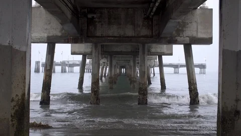Grey waves breaking under a wooden pier in Manhattan Beach, California Vidéo 93461205