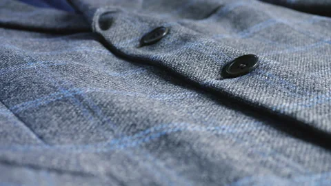 Grey wool blazer with blue plaid pattern and dark buttons close-up details. Stock Footage 346182449