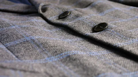 Grey wool blazer with blue plaid pattern and dark buttons close-up details. Stock Footage 346182526
