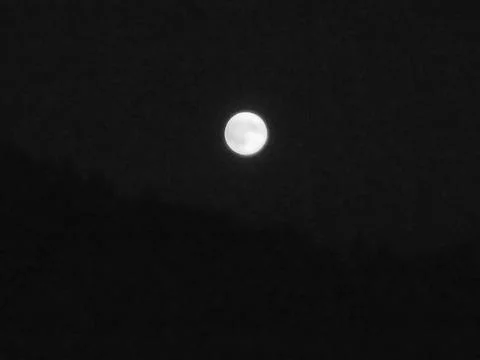 Greyscaled image - Moon in complete darkness with slightly yellow color tone. Stock Photos