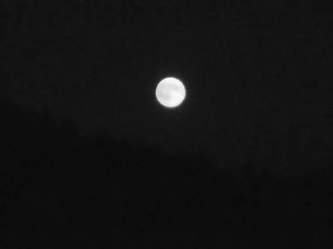 Greyscaled image - Moon in complete darkness with slightly yellow color tone. Stock Photos