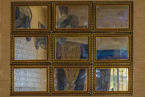 A grid of nine antique mirrors reflecting interior elements in a cozy room. Stock Photos