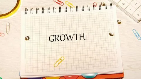 A grid notebook lies open on a desk, boldly displaying the word growth. Colorful Stock Photos