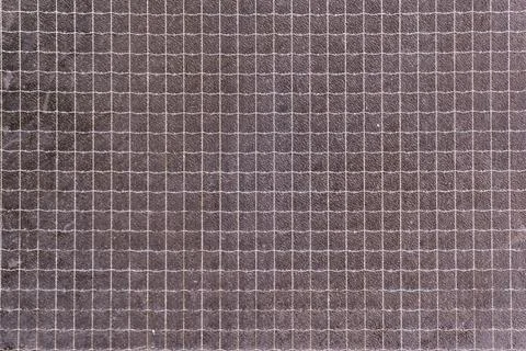 Grid pattern creating a precise mesh of small squares on a dark, textured s.. Stock Photos