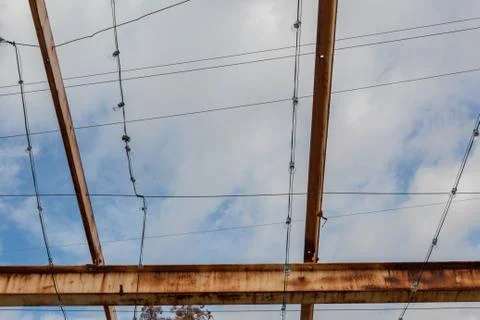 Gridwork of overhead beams, painted and rusted, against a blue sky Stock Photos