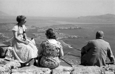 Griechenland Griechenland - Ein Mann und zwei Frauen sitzen auf einer Klip... Stock Photos
