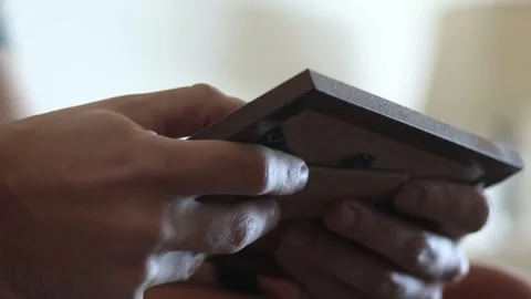 Grieving young man holding picture frame, reminiscing, remembering, 4K Stock Footage 340232541