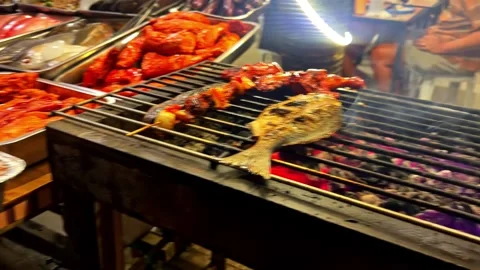 Grill with fish steaks and marinated meat cooking over glowing charcoal, then 库存影片 333885587