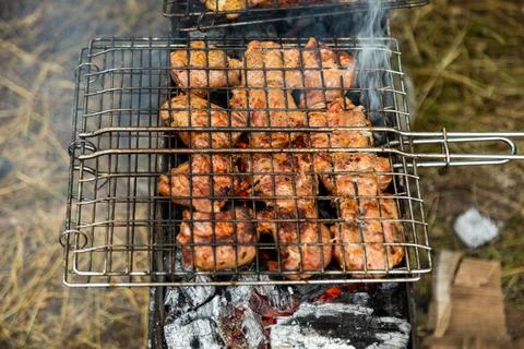 Grill grate with beef meat on a brazier with flaming charcoal Stock Photos