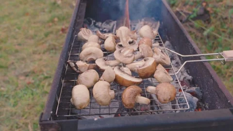 A grill grate with champignons is grilled over coals on a grill grate close-up Vídeos de archivo 318434745