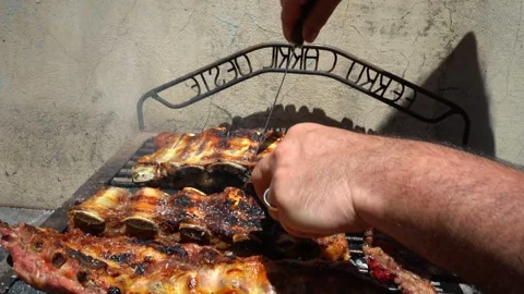 Grill man checking and turning meat on grill to achieve more even cooking. Video stock 293366631