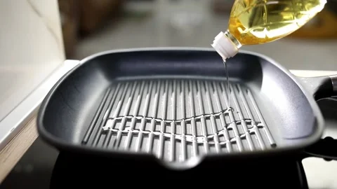 Grill pan is poured with oil. Preparing the pan before frying. Stock Footage 244133339