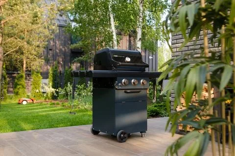 Grill set up in a backyard with trees and a building in the background duri.. Stock Photos