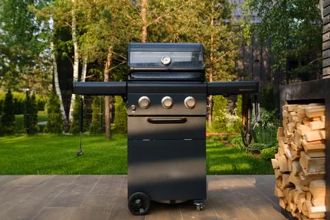 Grill set up in a backyard with trees and a building in the background duri.. Stock Photos