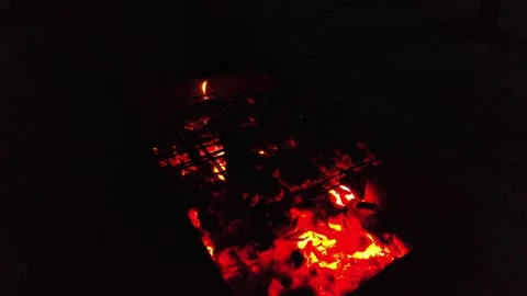 Grill set up with hot coals and flames at night near a campfire to cook meat and Stock Footage 331370624