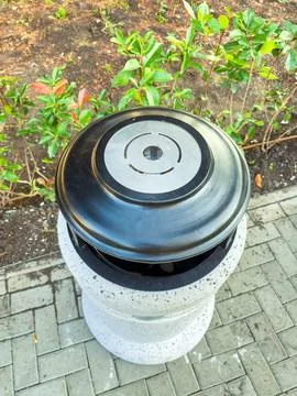 Grill setup on a stone pedestal surrounded by greenery in a garden setting Stock Photos
