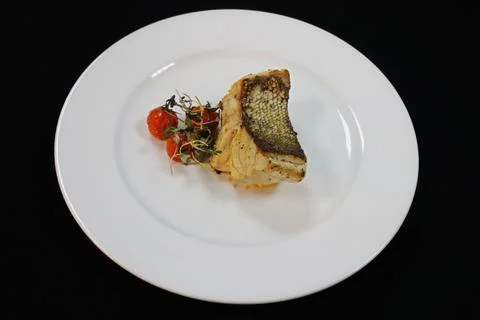Grilled atlantic cod fish fillet on a white plate with cherry tomato Stock Photos