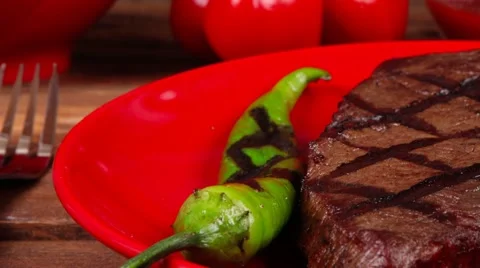 Grilled bbq roast beef steak on red plate with green chili pepper Vídeos de archivo 52703226