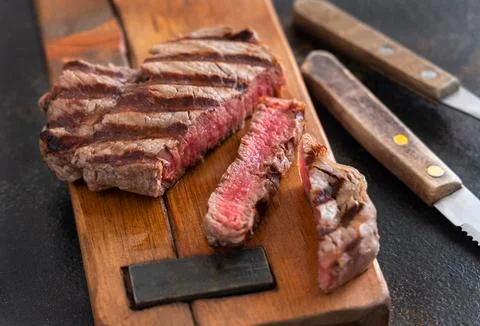 Grilled beef fillet steak with herbs and spices on dark table close up Stock Photos