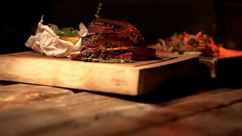 Grilled beef rib and fresh avocado salad on wooden cutting boards, close-up Vídeo Stock 83425733