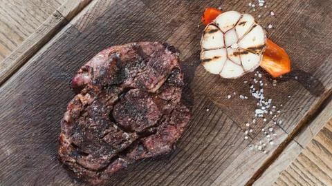 Grilled beef steak ribeye medium rare on wooden cutting board with slice of p Stock-Fotos