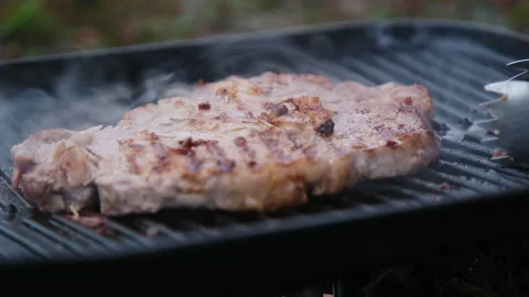 Grilled beef steak with spices on the grill with smoke. Видео 222679004