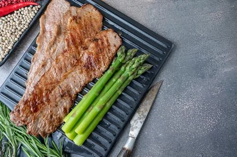 Grilled beef, thin slices of beef bacon on a cutting board with asparagus g.. Stock Photos